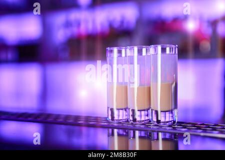 Una serie di shot di alcolici in due tonalità sul banco del bar di una discoteca Foto Stock