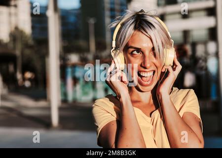 Donna entusiasta che ama ascoltare musica con le cuffie all'aperto. Foto Stock