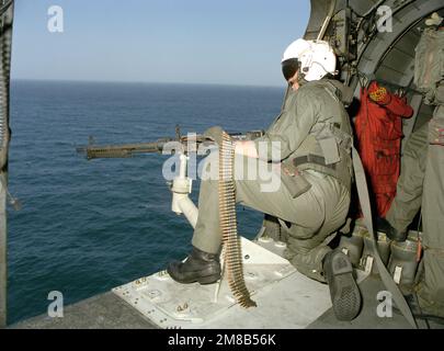 Un membro dell'equipaggio a bordo di un elicottero anti-sottomarino Squadron 8 (HS-8) SH-3H Sea King elicottero si prepara a sparare una mitragliatrice M-60D 7,62mm durante una missione di addestramento. Il Sea King è situato a bordo della COSTELLAZIONE della portaerei USS (CV-64). Paese: Oceano Pacifico (POC) Foto Stock