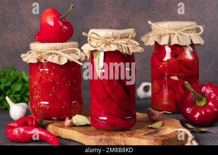 Vari tipi di peperoni sottaceto - peperoncini, peperoni dolci con aglio e peperoni in salsa di pomodoro Foto Stock