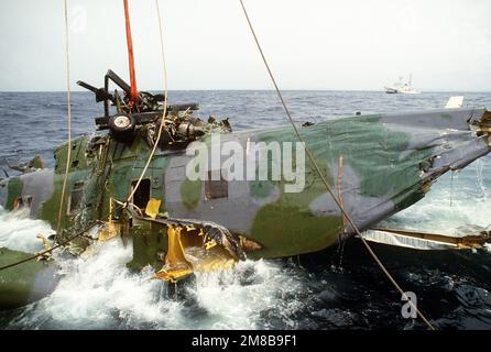 Una gru a bordo della nave di salvataggio giapponese SHIN TATSU MARU fa salire un elicottero Jolly Greene Giant dell'aeronautica HH-3E dall'oceano a 5,6 miglia al largo della costa di Okinawa, Giappone, dove si è schiantata durante un volo di addestramento notturno. Una grande pattuglia di classe Shiretoko, in alto a sinistra, dell'Agenzia giapponese per la sicurezza marittima, mantiene l'area libera man mano che l'operazione procede. Paese: Sconosciuto Foto Stock