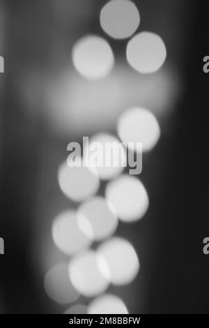 Bellissimi cerchi bokeh sfocati e sognanti che galleggiano intorno all'aria in bianco e nero. Foto Stock