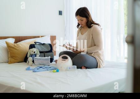 Asiatico donna incinta prenatale calendario pianificatore e baby monitor utensili, contenitore preparazione per il concetto di gravidanza. Foto Stock