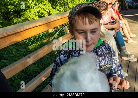 Chelyabinsk, Russia - 01 giugno 2022. Un ragazzo carino mangia caramella di cotone con appetito. Foto Stock