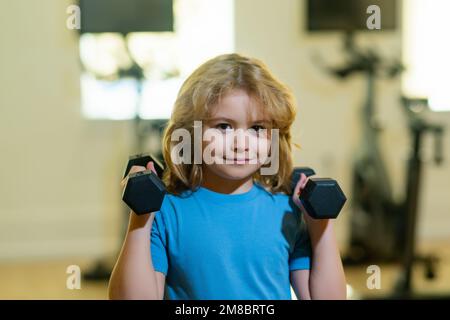 Bambino ragazzo pompare i muscoli bicipiti con manubri. Bambino in palestra. Fitness bambini con manubri. Foto Stock