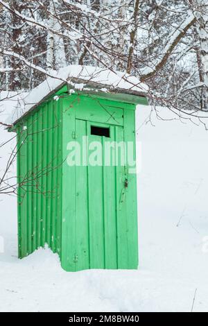 rustico bagno in legno all'aperto in una foresta innevata Foto Stock