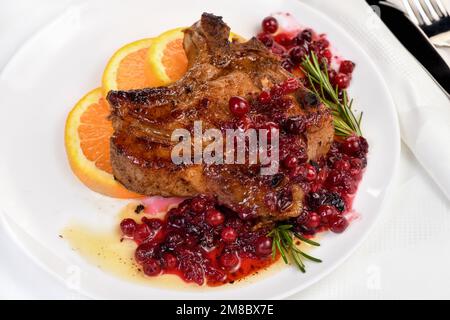 Braciole di maiale fritte servite con salsa ai mirtilli con arancia e rosmarino. Sono eleganti per un pranzo o una cena. Foto Stock