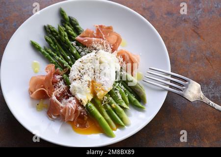 Uova Benedetto con parmigiano, asparagi verdi e prosciutto di Parma Foto Stock