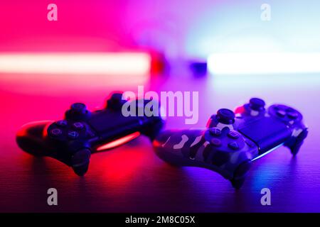 Due gamepad su un tavolo di legno con retroilluminazione rossa e blu. Foto Stock