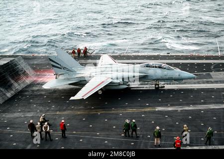 Gli equipanti della piattaforma di volo guardano come un F-14A Tomcat Aircraft di Fighter Squadron 154 (VF-154), il suo scarico del motore che colpisce il deflettore di esplosione, inizia il suo lancio da una catapulta sulla portaerei USS Constellation (CV-64) durante il PACEX '89. Soggetto operativo/Serie: PACEX '89 Paese: Sconosciuto Foto Stock