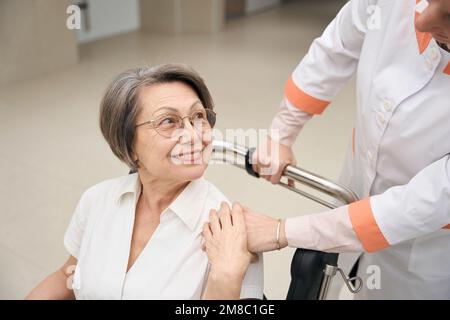 La donna con disabilità si sposta su una sedia a rotelle Foto Stock