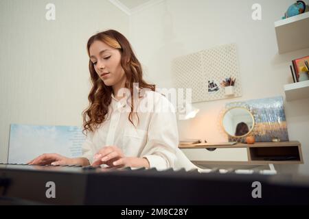 Musicista calmo e focalizzato che pratica strumenti musicali elettronici Foto Stock