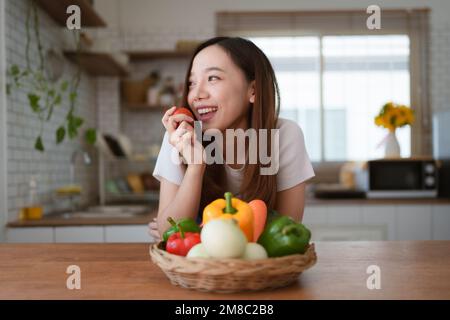 Ritratto di bella giovane donna asiatica che fa insalata a casa. Cucinare cibo e momento di stile di vita Foto Stock