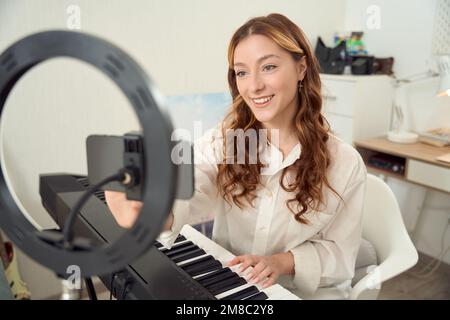 Vlogger si prepara a trasmettere in live streaming la sua lezione di musica per il pubblico online Foto Stock