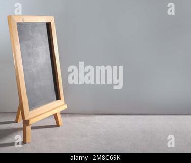 Un primo piano di una lavagna bianca con una cornice di legno su sfondo grigio Foto Stock