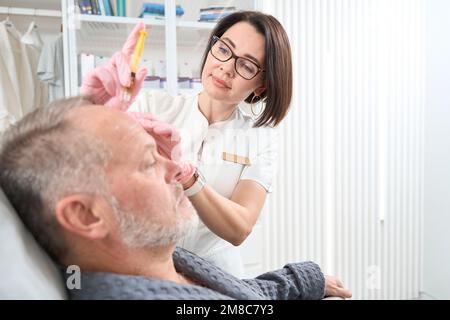 Donna medico fa iniezioni nella fronte di un paziente Foto Stock