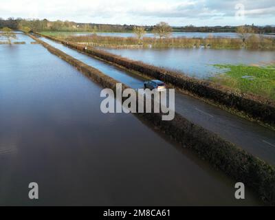 Sutton St Nicholas, Herefordshire, Regno Unito – Venerdì 13th gennaio 2023 – UK Weather – veduta aerea dei veicoli che attraversano le acque alluvionali dal vicino fiume Lugg su una strada rurale tra Sutton St Nicholas e Hereford. Dopo giorni di pioggia, fiumi locali come il fiume Lugg, il fiume Teme e il fiume Wye sono tutti a livelli molto alti. Più previsioni di pioggia. Foto Steven Maggio / Alamy Live News Foto Stock