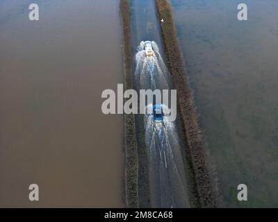 Sutton St Nicholas, Herefordshire, Regno Unito – Venerdì 13th gennaio 2023 – UK Weather – veduta aerea dei veicoli che attraversano le acque alluvionali dal vicino fiume Lugg su una strada rurale tra Sutton St Nicholas e Hereford. Dopo giorni di pioggia, fiumi locali come il fiume Lugg, il fiume Teme e il fiume Wye sono tutti a livelli molto alti. Più previsioni di pioggia. Foto Steven Maggio / Alamy Live News Foto Stock