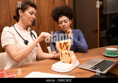 Donna afro-americana sorridente che guarda un campione di pavimento pelvico Foto Stock