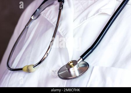 Stetoscopio medico in metallo nero su uniforme medico bianco in ospedale. Foto Stock