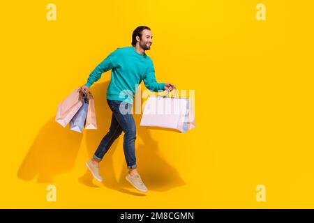 Foto a tutta lunghezza di ragazzo allegro vestito teal vestito jumping alta tenuta occasioni vuoto spazio isolato giallo sfondo Foto Stock
