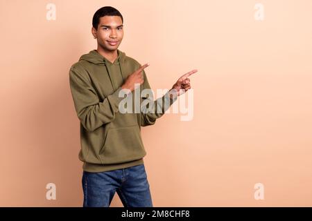 Foto del ragazzo studente giovane uomo indossare cachi sportswear felpa con cappuccio dita dirette beffa apertura nuovo spot negozio isolato su sfondo di colore beige Foto Stock