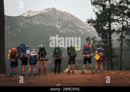 Un gruppo di turisti con grandi zaini è in piedi su una roccia. Il Monte Olympus è sullo sfondo. Lycian sentiero Turchia. Foto Stock