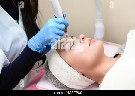 Un cosmetologo esegue una procedura di ringiovanimento mesoterapico con l'aiuto di dermapen, una visita ad un cosmetologo. Foto Stock