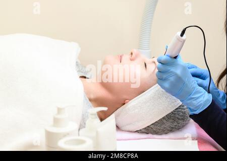 Un cosmetologo esegue una procedura di ringiovanimento mesoterapico con l'aiuto di dermapen, una visita ad un cosmetologo. Foto Stock