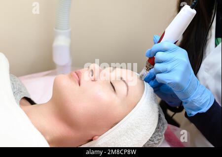 Un cosmetologo esegue una procedura di ringiovanimento mesoterapico con l'aiuto di dermapen, una visita ad un cosmetologo. Foto Stock