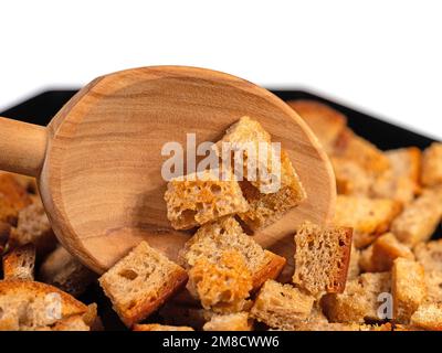 In primo piano, tostate i cubetti di pane su un cucchiaio di legno Foto Stock