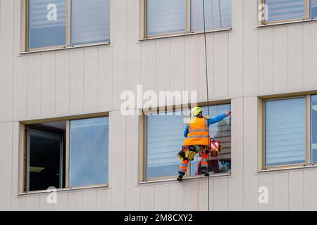 Minsk, Bielorussia - 11 aprile 2022: Il climber industriale lava le finestre sulla facciata di un edificio. Vista laterale Foto Stock