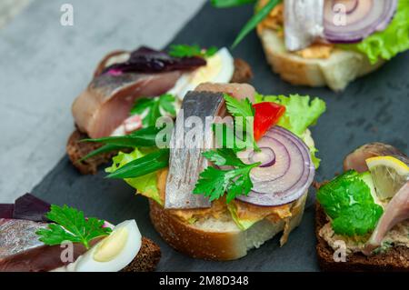Toast con aringhe salate, pate, cipolla, uovo, lattuga, pomodoro e barbabietola. Cucina scandinava. Banner, menu, luogo della ricetta per il testo, vista dall'alto. BUFF Foto Stock