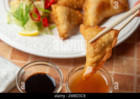 Wontons cinesi con salsa dolce al peperoncino e bastoncini tritare gnocchi fritti asiatici con salsa di soia su piatto bianco. Gnocchi fritti asiatici wontons con soia Foto Stock