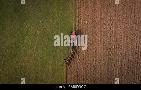 ripresa aerea del campo di aratura del trattore in campagna durante la stagione autunnale Foto Stock