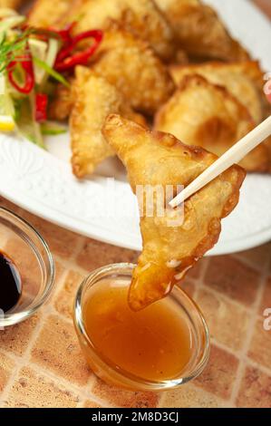 Wontons cinesi con salsa dolce al peperoncino e bastoncini tritare gnocchi fritti asiatici con salsa di soia su piatto bianco. Gnocchi fritti asiatici wontons con soia Foto Stock