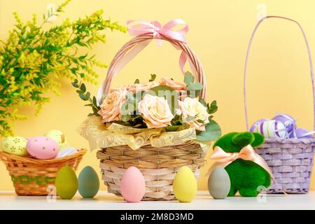 Pasqua composizione ancora vita. Un cesto con fiori e uova, un coniglio giocattolo sul tavolo. Foto Stock