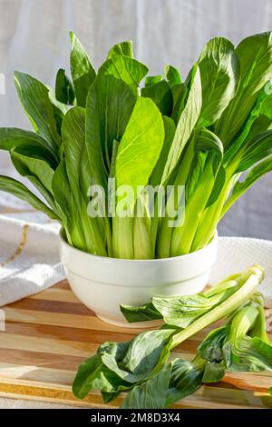 Verde crudo cavolo cinese pak choi o bok choy verdure del bambino sull'asse di legno nella cucina. Foto Stock