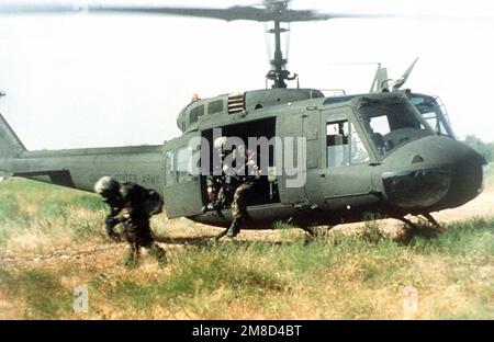 I soldati che indossano l'attrezzatura Mission-Oriented Protective Posture Response Level 4 (MOPP-4) salgono da un elicottero Iroquois UH-1. Paese: Sconosciuto Foto Stock