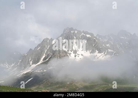 Montagne innevate nella nebbia. Vista panoramica sulle cime montane Foto Stock