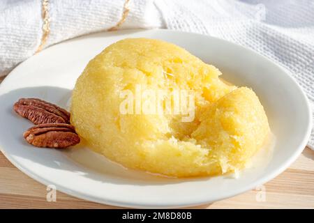 Dolce giallo turco formaggio da dessert halva Hosmerim sul piatto bianco in cucina. Foto Stock