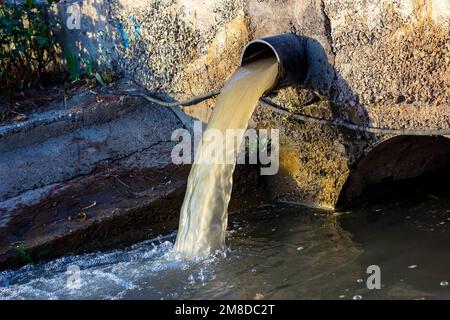 Il tubo di scarico di acque reflue scarica l'acqua sporca contaminata nel fiume. Concetto di inquinamento idrico, contaminazione ambientale. Foto Stock