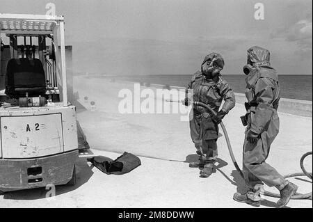 Due soldati del 71st° Reggimento chimico, 25th° Divisione Fanteria (Light), spruzzano una soluzione di decontaminazione su un carrello elevatore a forche utilizzato per la manipolazione di munizioni chimiche. I soldati stanno partecipando a un esercizio progettato per testare la capacità dell'unità di rilevare e mitigare una perdita chimica. Base: US Army Chemical Activity Paese: Johnston Atoll Foto Stock