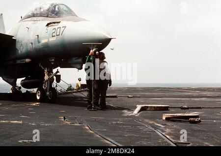 Gli equipaggi della piattaforma di volo a bordo della portaerei USS INDEPENDENCE (CV-62) si trovano vicino a un aereo Fighter Squadron 21 (VF-21) F-14A Tomcat per guardare l'avvicinamento di un velivolo S-3A Viking durante l'operazione Desert Shield. Soggetto operativo/Serie: DESERT SHIELD Paese: Golfo di Oman Foto Stock