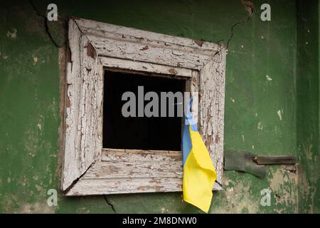 La bandiera dell'Ucraina è appesa alla finestra di un edificio residenziale distrutto, la guerra e il bombardamento di edifici residenziali russi in Ucraina Foto Stock