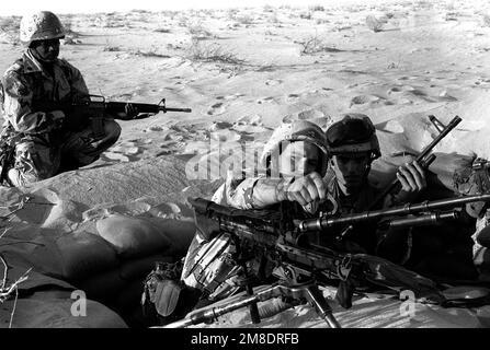 I membri di Heavy Weapons PLT., Weapons Co., 1st BN., 7th Marines, cambiano il barile su una mitragliatrice M-60E3 7,67mm durante l'operazione Desert Shield. Un altro membro della compagnia, armato di un fucile M-16A2, custodisce il posto. Subject Operation/Series: SCUDO DEL DESERTO Paese: Arabia Saudita (SAU) Foto Stock