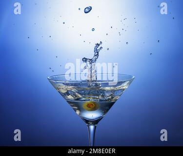 Una foto da cocktail di un'oliva è caduta in un martini sporco. Ripresa con illuminazione da studio e strobo di sincronizzazione ad alta velocità. Ideale per menu, Web o pubblicazioni Foto Stock