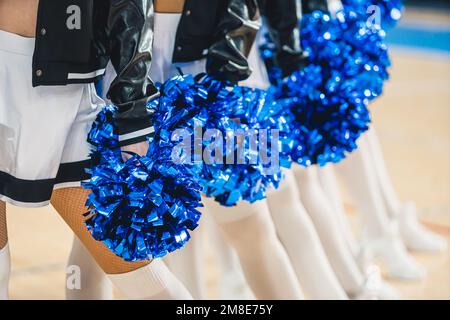 Cheerleaders dinamici in calzini bianchi che tengono pom pom pom mostrando spirito di squadra. Foto Stock