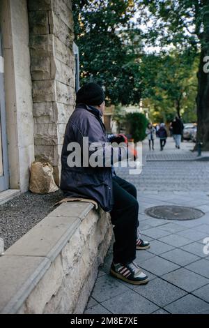 Un triste uomo senza casa chiede denaro per strada. Foto Stock