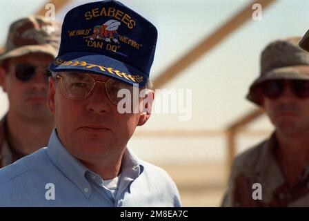 Il Segretario della Marina H. Lawrence Garrett III, durante l'operazione Desert Shield, fa una berretta di Seabees mentre visita un campo di battaglione di costruzione. Soggetto operativo/Serie: SCUDO DEL DESERTO Paese: Arabia Saudita (SAU) Foto Stock